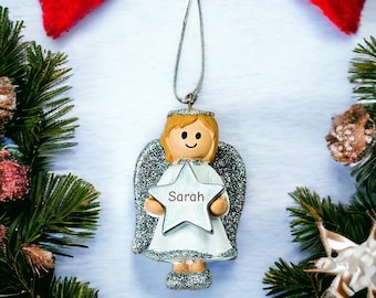 May include: A silver glitter angel Christmas ornament with a white star that says "Sarah" on it.