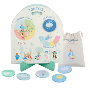May include: A wooden Peter Rabbit themed learning toy with a rotating dial to show the month and season, a movable slider to show the weather, and a dial to show the temperature. The toy also includes a small bag and several weather-themed tokens.