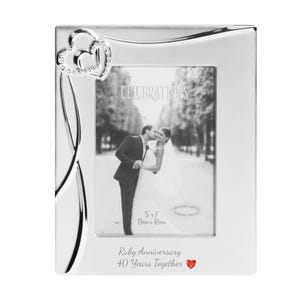 May include: Silver picture frame with a heart design and a red rhinestone. The frame is for a 5x7 inch photo and has the text "Celebrations" and "Ruby Anniversary 40 Years Together" on it.