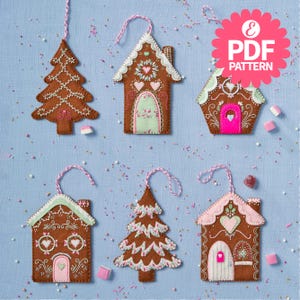 Könnte beinhalten: Eine Sammlung von Weihnachtsbaumschmuck aus Filz in Form von Lebkuchenhäusern und -bäumen. Die braunen Ornamente haben weiße, rosa und grüne Akzente. Jeder Schmuck hat eine Schlaufe zum Aufhängen. Der Text "PDF PATTERN" ist ebenfalls enthalten.