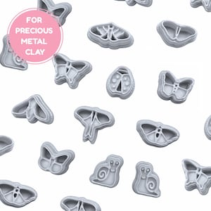 May include: A selection of grey metal clay cutters in insect and nature designs, such as butterflies, moths, and snails. The image features a pink circle with the text "FOR PRECIOUS METAL CLAY".