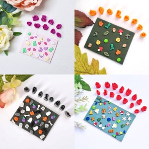 May include: A selection of colourful polymer clay cutters in diverse shapes, including hearts, leaves, and seasonal designs. The cutters are arranged on small, coloured cards, ideal for crafting projects. The image showcases a variety of themes, such as autumn, Halloween, and Christmas.