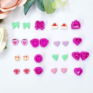 May include: A set of 20 pink and green polymer clay cutters in various shapes, including hearts, bows, coffee cups, roses, and smiley faces. The cutters are arranged on a white surface.