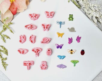 May include: A collection of pink plastic cookie cutters in various insect and animal shapes, including butterflies, dragonflies, and snails. Also included are small, colorful, decorative insect and animal-shaped embellishments.