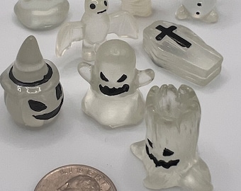 May include: A set of nine translucent Halloween-themed figurines, including a ghost, a bat, a coffin, a pumpkin, a snowman, and a tree. The figurines are all white with black details and are approximately 2 inches tall.