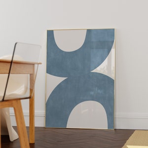 May include: A framed abstract art print with a blue and white design. The print features two large, overlapping circles in a light blue color with a white background.