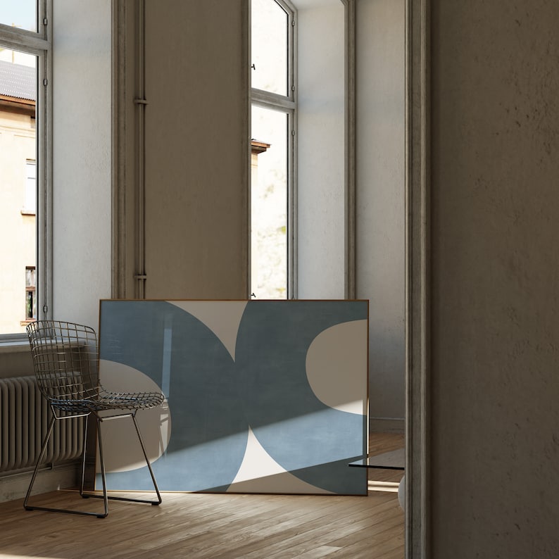 May include: A large abstract painting with a blue and white design hangs on a wall in a room with a window and a chair. The painting features two large, curved shapes in a light blue color, with a white background.