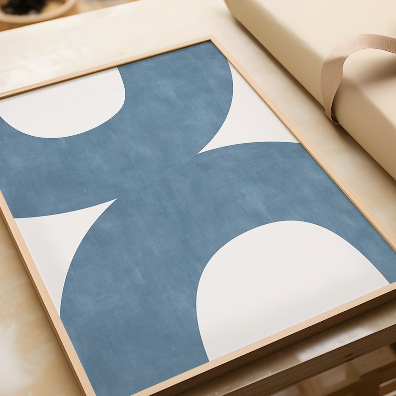 May include: A framed print with a geometric design featuring two overlapping semi-circles in shades of blue and white.