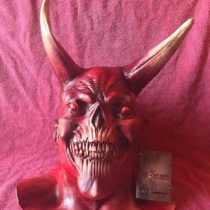 May include: Red devil mask with horns, sharp teeth, and glowing eyes. The mask is made of latex and has a realistic look. The mask is labeled "Ghoul-ish Creations".