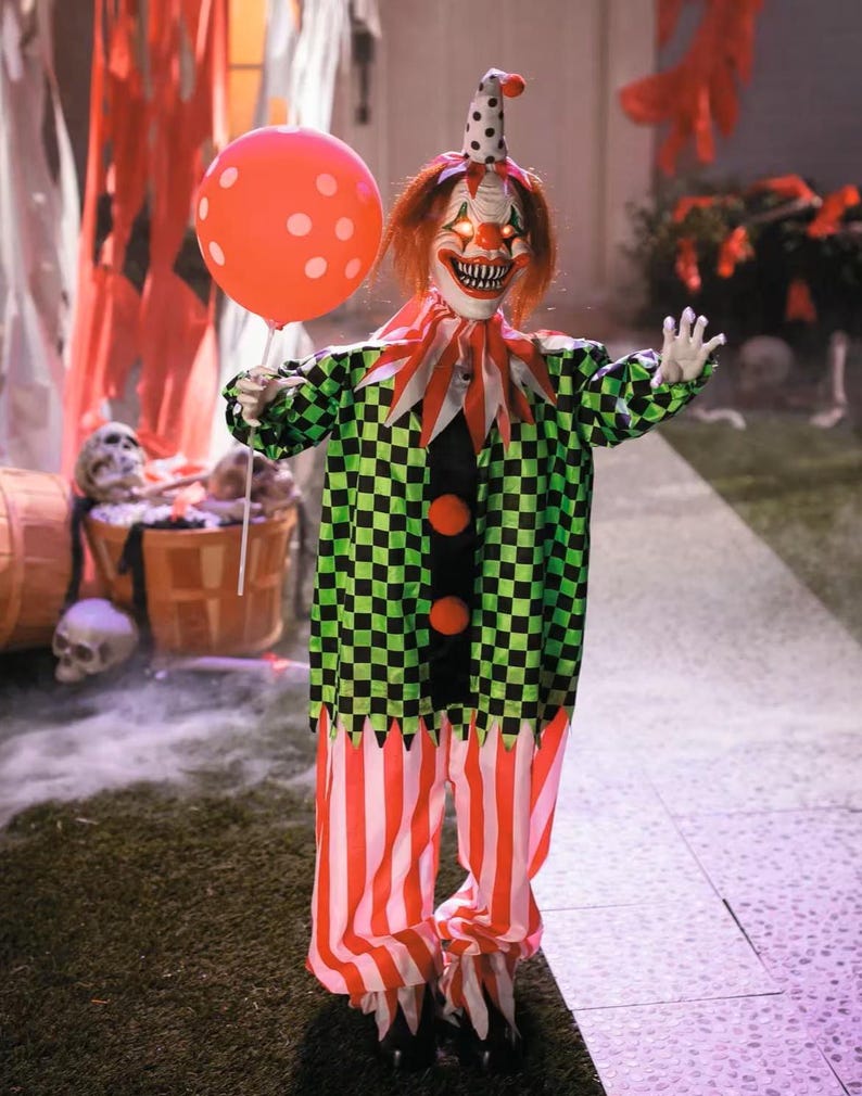May include: A Halloween clown decoration with a menacing expression. The clown wears a green and black checkered jacket, red and white striped pants, and holds an orange balloon with white polka dots. The clown has red hair and a polka-dot hat.