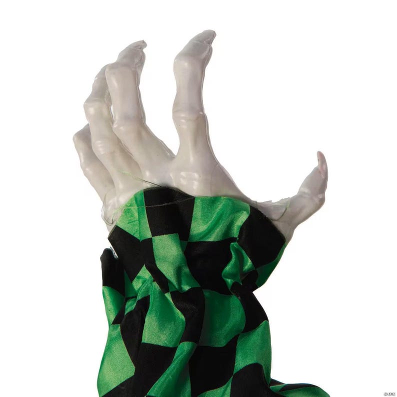 May include: A white, skeletal hand with a green and black checkered fabric sleeve. The hand is posed in a grasping position, with fingers slightly curved. The fabric has a repeating pattern of black squares on a green background.