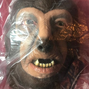 May include: A werewolf mask made of latex with brown fur, a detailed face, and sharp teeth. The mask is packaged in a clear plastic bag.