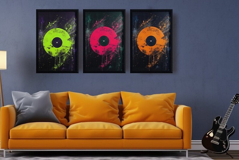 Puede incluir: Tres impresiones enmarcadas de discos de vinilo coloridos sobre un fondo negro. Los discos son verde, rosa y naranja. Las impresiones est&aacute;n colgadas en una pared azul sobre un sof&aacute; amarillo.