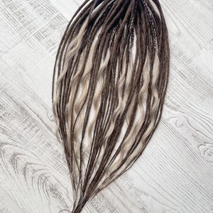 May include: A set of brown and blonde synthetic dreadlocks. The dreadlocks are long and wavy.