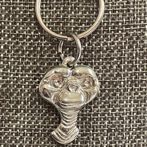 May include: Silver keychain featuring a detailed E.T. character head with large eyes and a long neck.