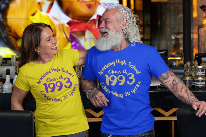 May include: Two people wearing matching yellow and blue t-shirts with the text "Academy High School Class of 1993 Celebrating 30 years".