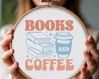 May include: A white embroidery hoop with the text "BOOKS AND COFFEE" in orange and blue. The text is in a retro font style. There is a stack of books and a cup of coffee in the design.