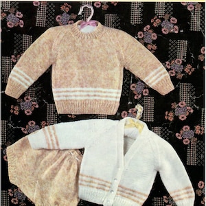 Puede incluir: Un conjunto de punto para bebé compuesto por un jersey y un pantalón a juego en rosa y blanco. El jersey tiene cuello redondo y mangas largas con rayas blancas. El pantalón tiene una cintura ancha y rayas blancas en las piernas. El conjunto está hecho para un bebé de 19-21 pulgadas (48-53 cm).