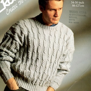 May include: A light grey cable knit jumper with a crew neck. The jumper is made of a soft, comfortable material and is perfect for everyday wear. The model is wearing the jumper with black trousers.
