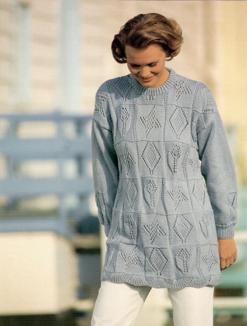 Może przedstawiać: Jaszek z dzianiny w jasnoniebieskim kolorze z geometrycznym wzorem. Sweter ma okrągły dekolt i długie rękawy.