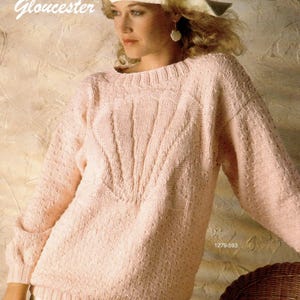May include: A light pink knitted sweater with a textured pattern and long sleeves. The sweater has a round neckline and a ribbed hem. The word "Gloucester" is printed in cursive on the upper left corner. The number "1279-593" is printed on the lower right corner.