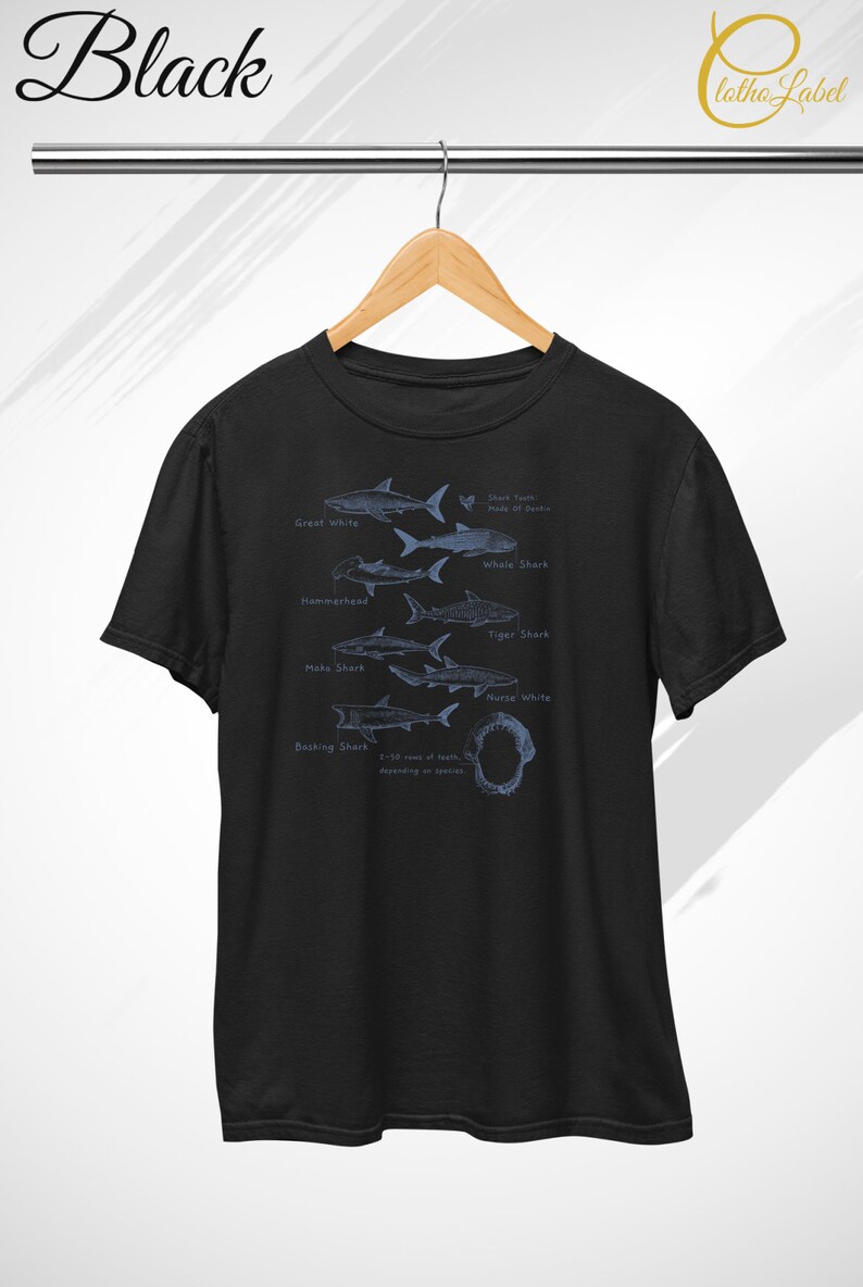 May include: Black t-shirt with a graphic of different shark species, including the Great White, Whale Shark, Hammerhead, Tiger Shark, Mako Shark, Nurse White, and Basking Shark. The graphic also includes the text "Shark Teeth, Made of Dentine" and "1-50 rows of teeth, depending on species."