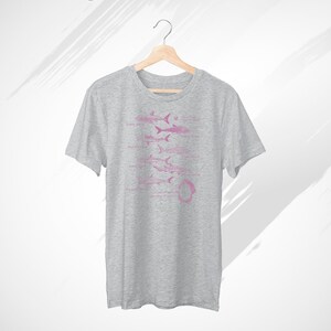 Pode incluir: Uma camiseta cinza mesclada com um gr&aacute;fico rosa de diferentes tipos de tubar&otilde;es. O texto "Grande branco", "Mako", "Tigre", "Touro", "Martelo" e "Tubar&atilde;o baleia" est&aacute; impresso abaixo dos tubar&otilde;es.