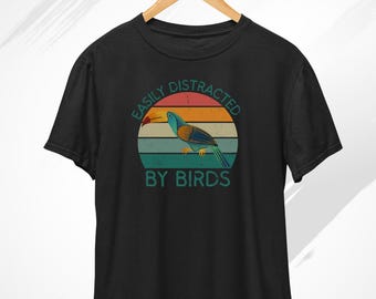 May include: Black t-shirt with a vintage-style graphic of a toucan with the text "Easily Distracted By Birds".