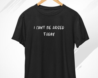 May include: Black t-shirt with the text "I CAN'T BE ARSED TODAY" in white, hanging from a wooden hanger. The word "Black" is written in cursive at the top left. The Clothe Label logo is in the top right.