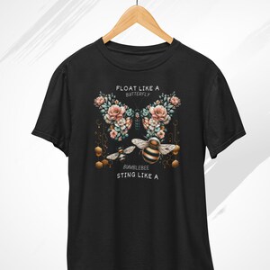 May include: Black t-shirt featuring a floral design and a bee. The text on the shirt reads "Float like a butterfly, bumblebee sting like a".