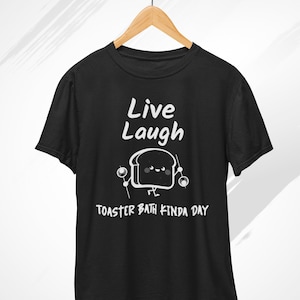 May include: Black t-shirt with a white graphic of a cartoon slice of bread holding drumsticks and the text "Live Laugh Toaster Bath Kinda Day".
