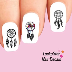May include: Three white fingernails each featuring a black dreamcatcher decal. One decal includes watercolor accents in blue, pink, and yellow. The text LuckyStar Nail Decals is printed in black with small pink and orange stars nearby.