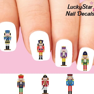 Può includere: Adesivi per unghie con disegni di soldati schiaccianoci colorati. Gli adesivi includono varie illustrazioni di schiaccianoci in rosso, blu, verde e viola, con il testo "LuckyStar Nail Decals" in alto a destra.