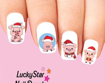 Può includere: Quattro unghie decorate con decalcomanie raffiguranti maialini dei cartoni animati che indossano cappelli da Babbo Natale rossi e bianchi. I maialini tengono un bastoncino di zucchero, sbirciano, tengono una tazza fumante e un regalo. Testo LuckyStar Nail Decals.