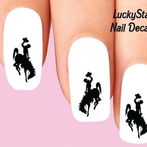 May include: Nail decals featuring a black silhouette of a rodeo cowboy riding a bucking bronco. The decals are applied to white nail polish. The text "LuckyStar Nail Decals" is visible in the upper right corner.