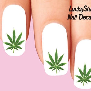 Puede incluir: Calcomanías para uñas con un diseño de hoja de cannabis verde sobre fondo blanco. La imagen muestra las calcomanías aplicadas en las uñas. El texto "LuckyStar Nail Decals" es visible en la esquina superior derecha.