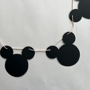 May include: Black and white Mickey Mouse themed garland with black paper cutouts of Mickey Mouse heads strung on white twine.