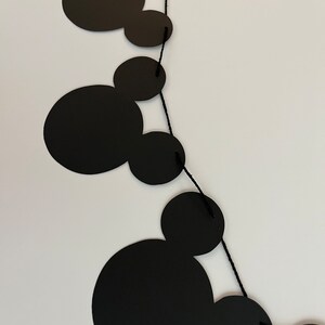 Puede incluir: Guirnalda de papel con tem&aacute;tica de Mickey Mouse en blanco y negro con cuerda negra. La guirnalda est&aacute; hecha de recortes de papel de cabezas de Mickey Mouse.