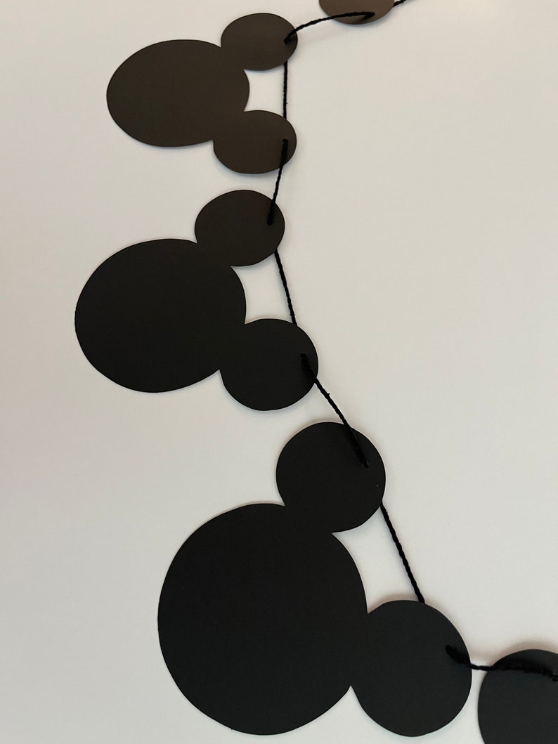 Puede incluir: Guirnalda de papel con tem&aacute;tica de Mickey Mouse en blanco y negro con cuerda negra. La guirnalda est&aacute; hecha de recortes de papel de cabezas de Mickey Mouse.
