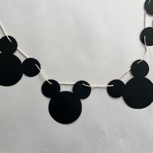 May include: Black and white Mickey Mouse themed paper garland with black circles and ears strung on white twine.