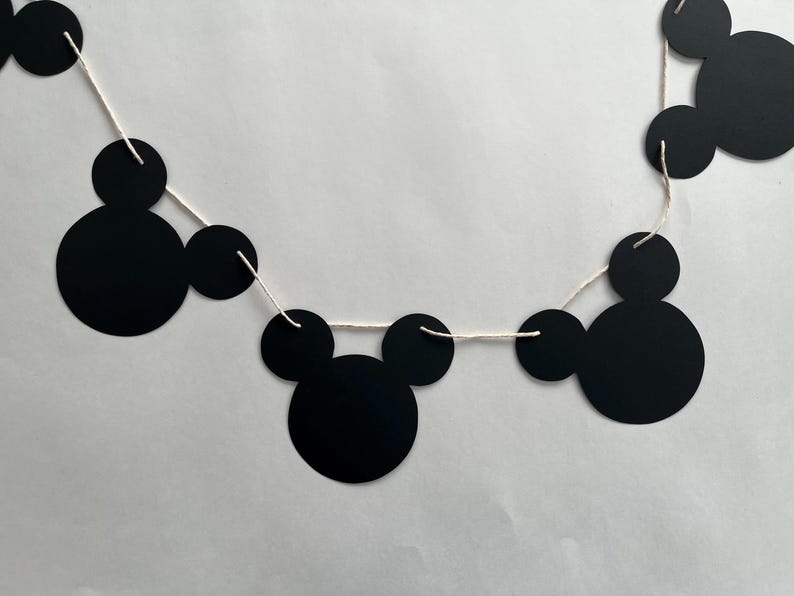 May include: Black and white Mickey Mouse themed paper garland with black circles and ears strung on white twine.