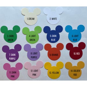 May include: A set of 14 Mickey Mouse-shaped paper cutouts in various colors, including cream, white, green, blue, purple, orange, red, yellow, and gold. Each cutout has a number and a color name printed on it.