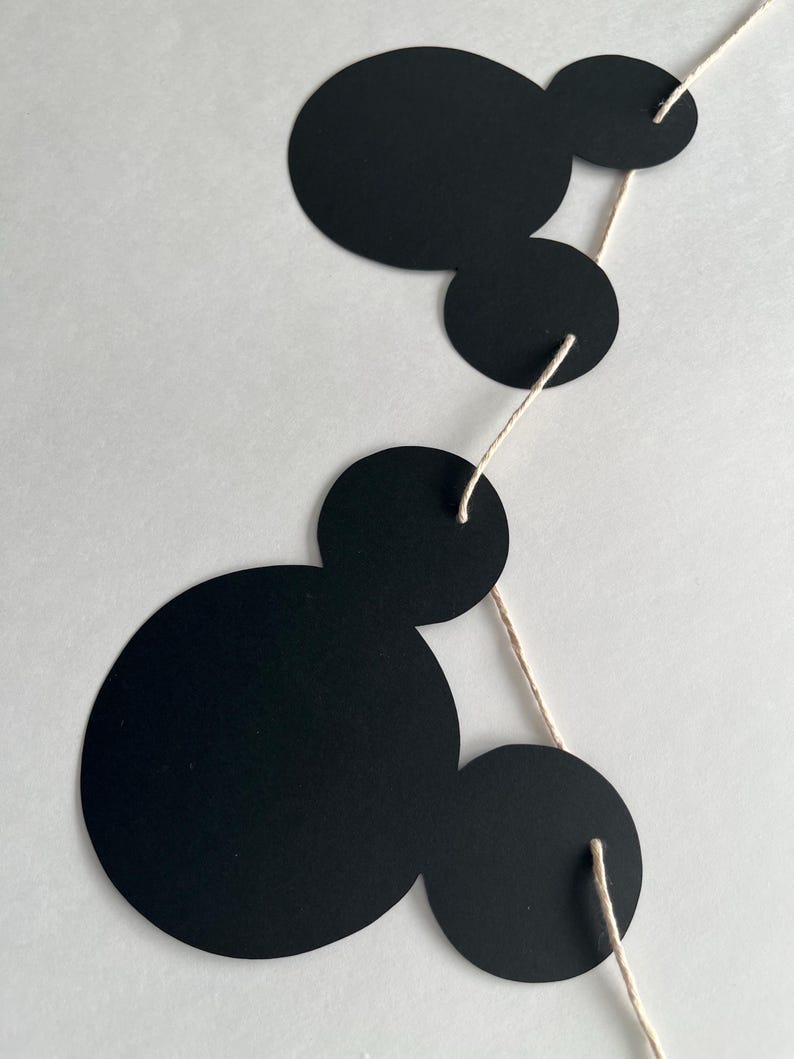 Puede incluir: Una guirnalda en blanco y negro con cinco c&iacute;rculos redondos conectados por una cuerda. Los c&iacute;rculos son de diferentes tama&ntilde;os y est&aacute;n dispuestos en un patr&oacute;n.