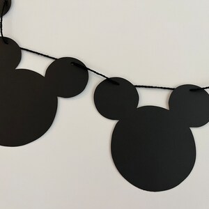 Puede incluir: Guirnalda de papel con tem&aacute;tica de Mickey Mouse en blanco y negro con cuerda negra. La guirnalda est&aacute; hecha de recortes de papel de cabezas de Mickey Mouse.