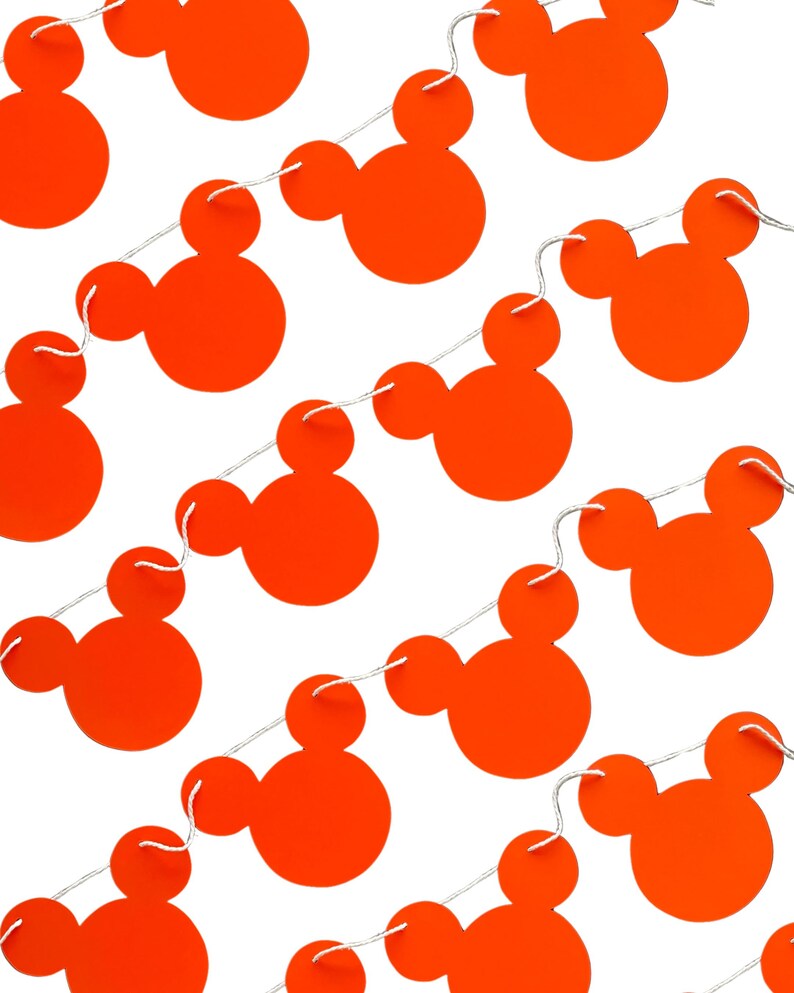 May include: A string of orange Mickey Mouse head cutouts strung together with white string. The cutouts are evenly spaced and the string is visible.