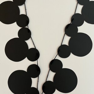 Puede incluir: Guirnalda de papel con tem&aacute;tica de Mickey Mouse en blanco y negro con cuerda negra. La guirnalda est&aacute; hecha de c&iacute;rculos con orejas de Mickey Mouse.