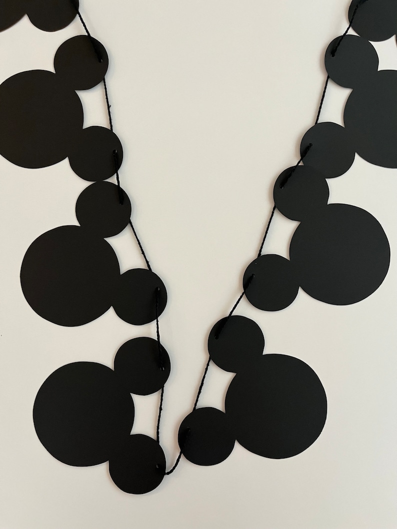 Puede incluir: Guirnalda de papel con tem&aacute;tica de Mickey Mouse en blanco y negro con cuerda negra. La guirnalda est&aacute; hecha de c&iacute;rculos con orejas de Mickey Mouse.
