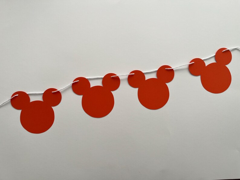 May include: Red paper Mickey Mouse head cutouts strung together with white string to create a party banner.