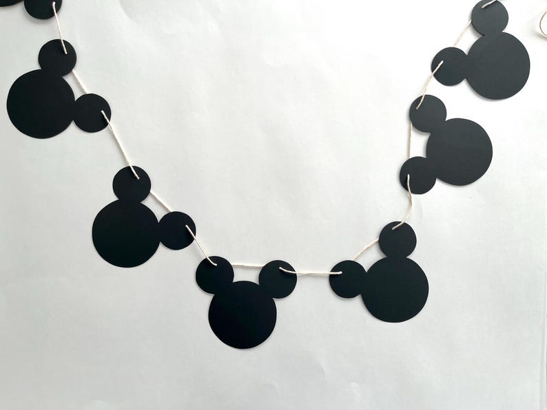 Puede incluir: Guirnalda de cabezas de Mickey Mouse en blanco y negro con una cuerda blanca. La guirnalda est&aacute; hecha de papel y tiene un total de 7 cabezas de Mickey Mouse.