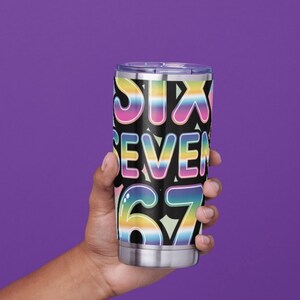 May include: A stainless steel tumbler with a black background and the words "SIX SEVEN 67" in a rainbow gradient font. The tumbler is held against a purple background.